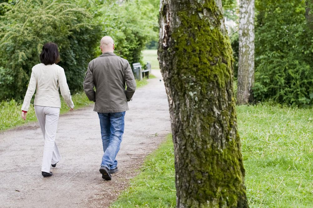 Eine Frau und ein Mann, die gemeinsam im Park spazieren gehen.