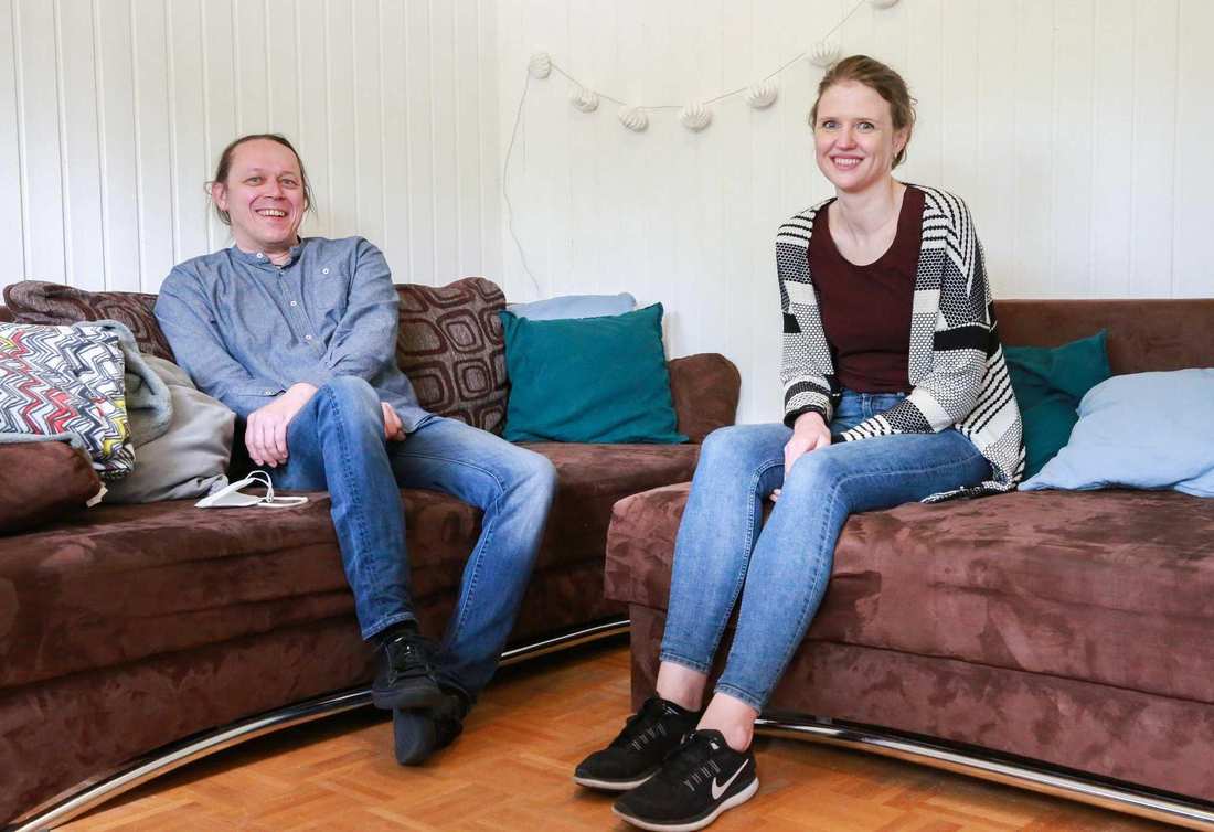 Ein Mann und eine Frau sitzen in einer Couch-Ecke. Sie lächeln.
