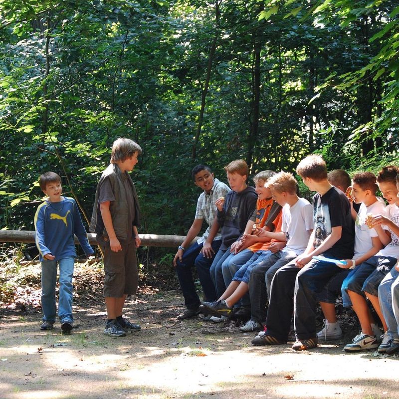 Eine Gruppe von Kindern, die auf einem umgefallenen Baum sitzen
