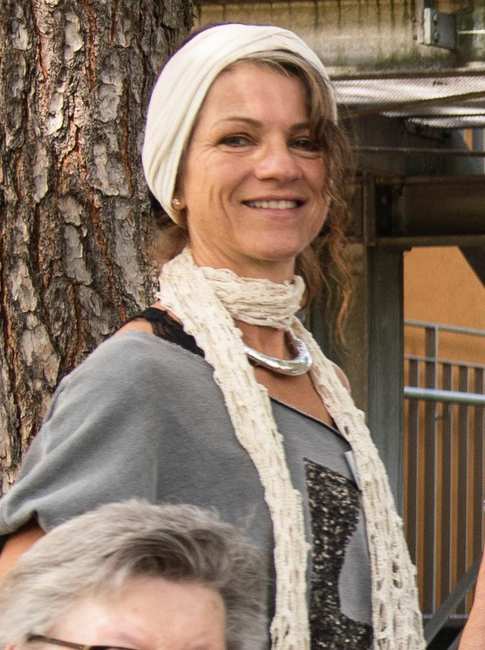 Portrait einer lächelnden Frau: Sie trägt ein weißes Tuch im Haar und ein weißes Halstuch.