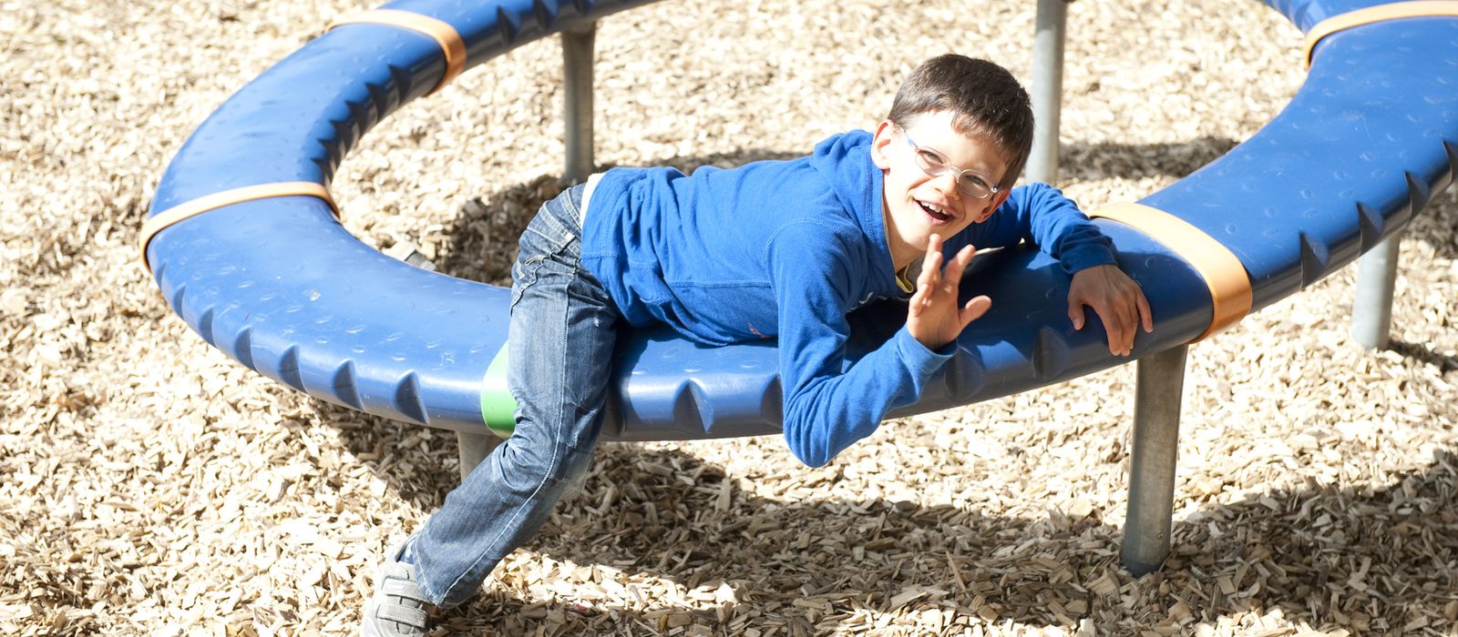 Ein Junge liegt auf einem Spielgerät auf einem Spielplatz.