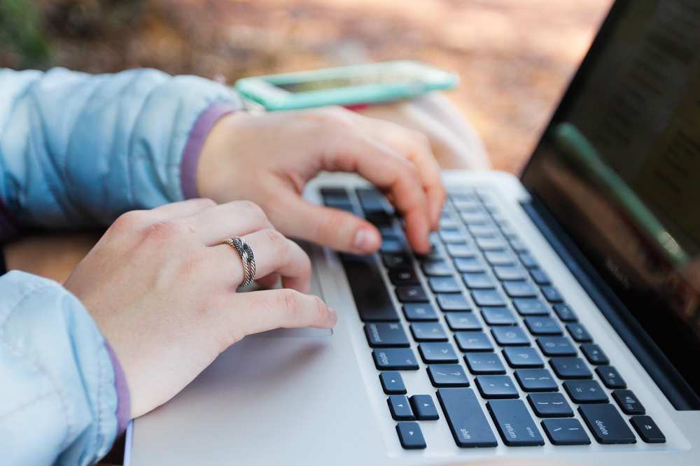 Zwei Frauenhände tippen auf einer Laptop-Tastatur.