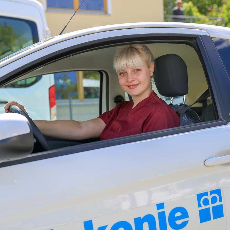 Eine Pflegekraft sitzt am Steuer eines Autos der Diakonie Erlangen. 