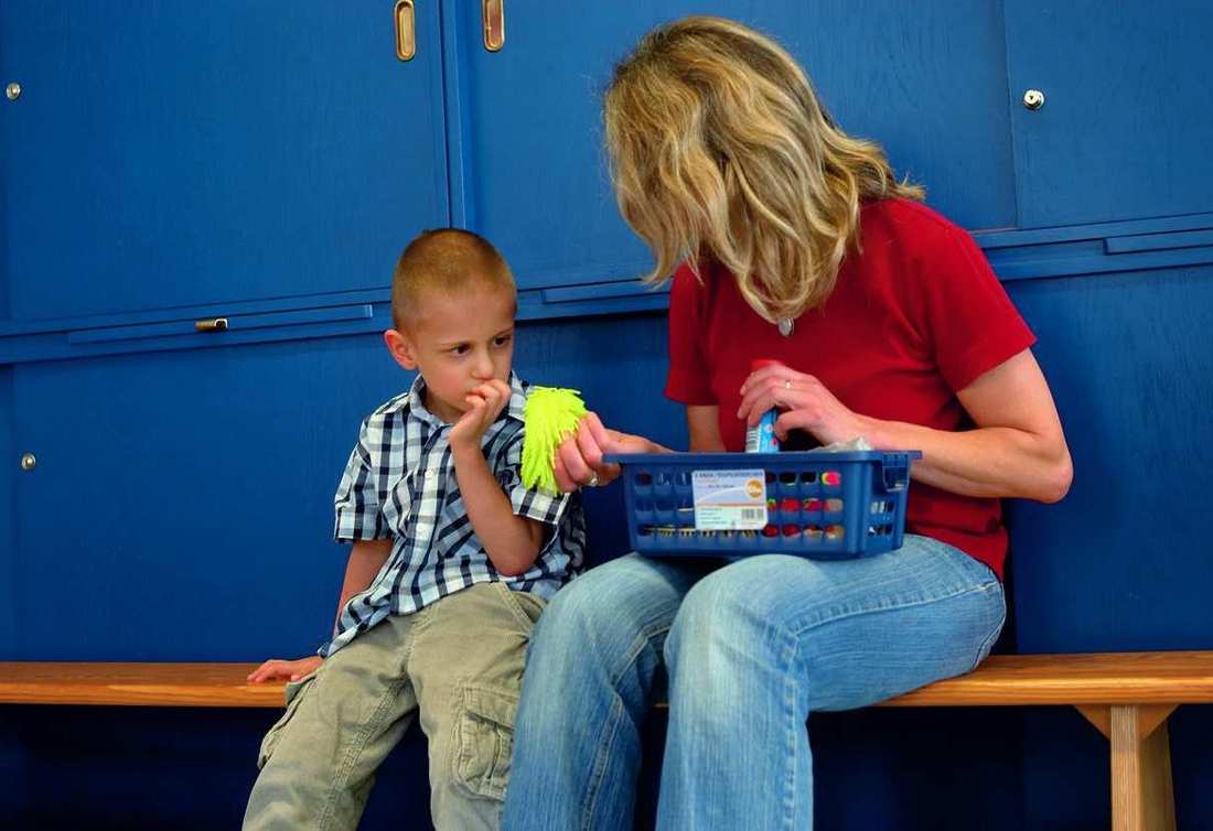 Eine Frau sitzt mit einem Kind auf einer Bank vor blauen Spindschränken