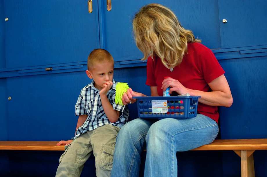 Eine Frau sitzt mit einem Kind auf einer Bank vor blauen Spindschränken