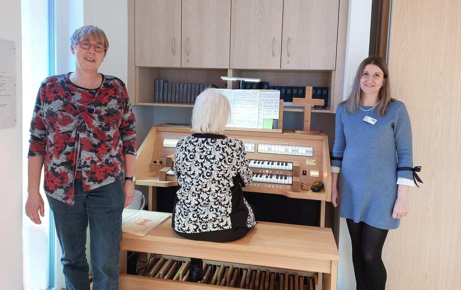 Seelsorgerin Petra Schnitzler und Pflegedienstleiterin Sylvia Polok freuen sich mit Pianistin Martha Lücking über die neue Orgel im Karl-Heller-Stift
