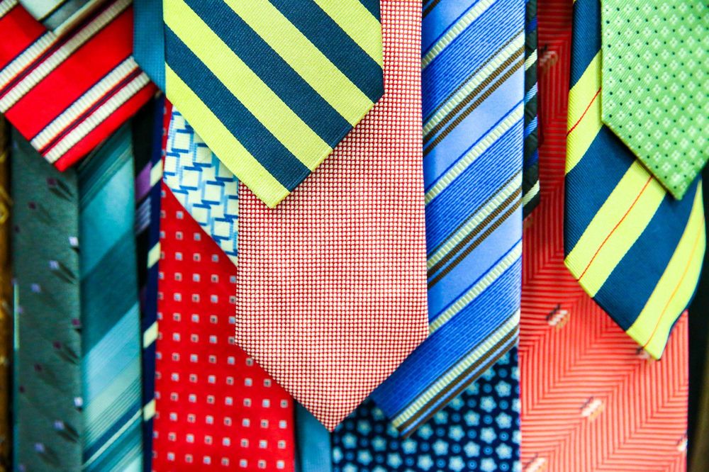 Verschiedene bunte Krawatten hängen übereinander und nebeneinander.