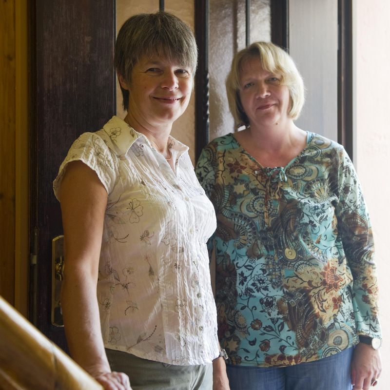 Zwei Frauen stehen in einer Tür und lächeln.