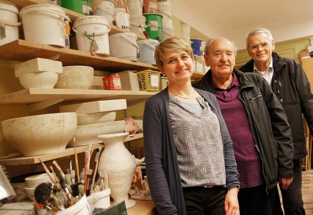 In einer Werkstatt: Ein Frau und zwei ältere Männer lächeln.