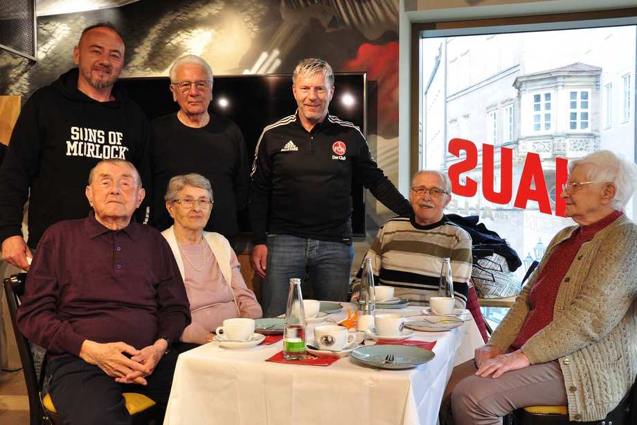 Thomas Ziemer, Dieter Nüssing und Helmut Rahner vom FCN-Traditionsteam stehen am Tisch von Seniorinnen und Senioren.